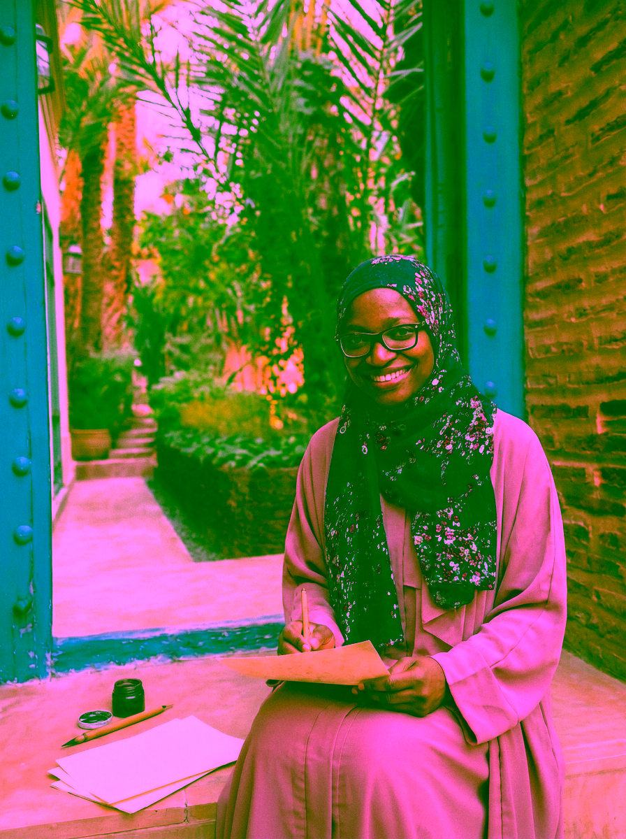 Halima Bashir seated in Morocco holding calligraphy paper